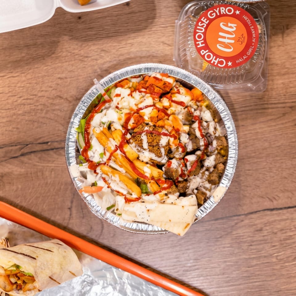 Overhead view of Greek takeout featuring a gyro bowl with fries and sauces, seasoned rice with meat, and a wrapped pita.